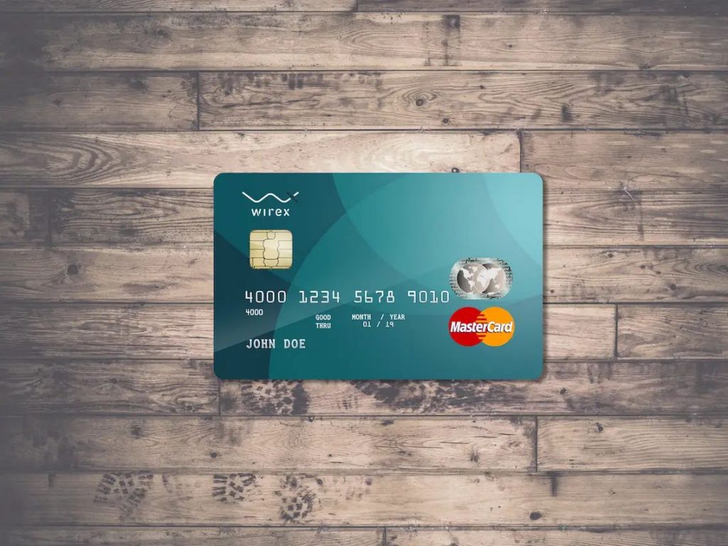 użytkownik dotykający ekranu smartfona ładując kryptowalutę na kartę debetową
