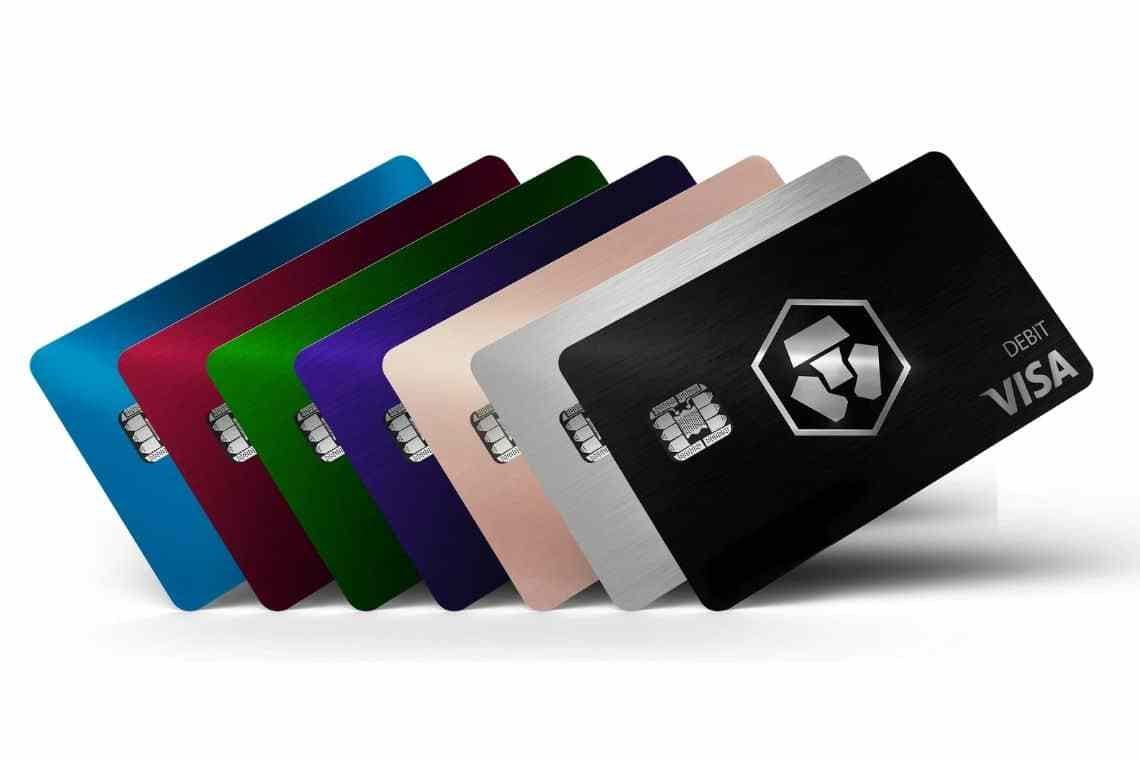 smartfon z aplikacją pokazującą saldo karty debetowej w kryptowalutach obok karty